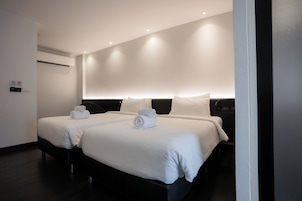 Habitación de hotel con dos camas, aire acondicionado de pared y cartel de no fumar.