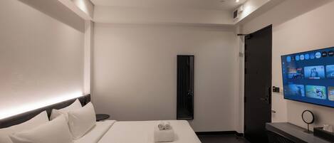 A hotel room with a bed, a desk, a TV, and a door.