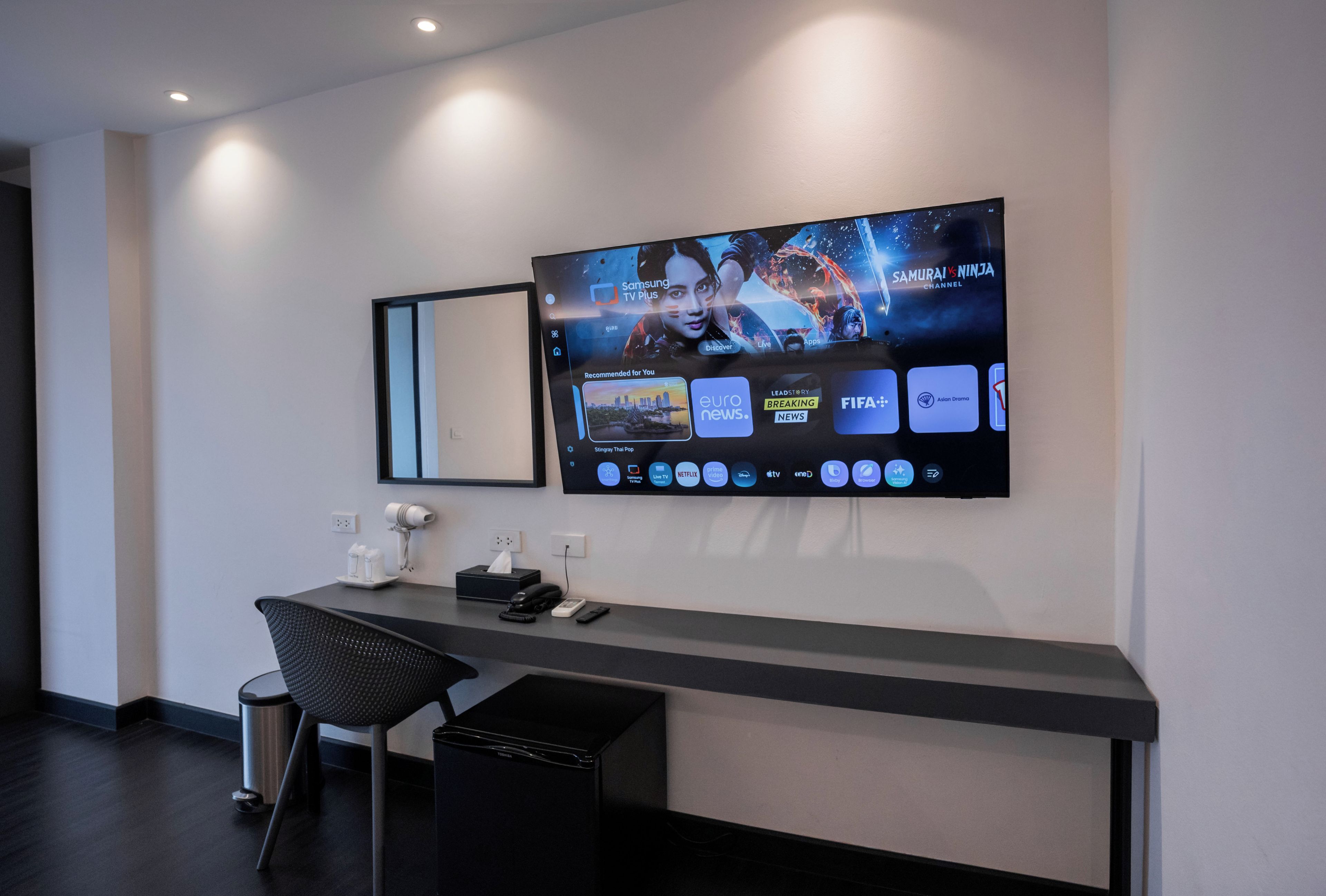 Un moderno mostrador de recepción con un televisor de pantalla plana mostrando la interfaz de un canal.