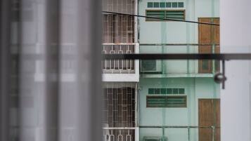 A multi-story building with a series of balconies and windows, some with metal grilles.