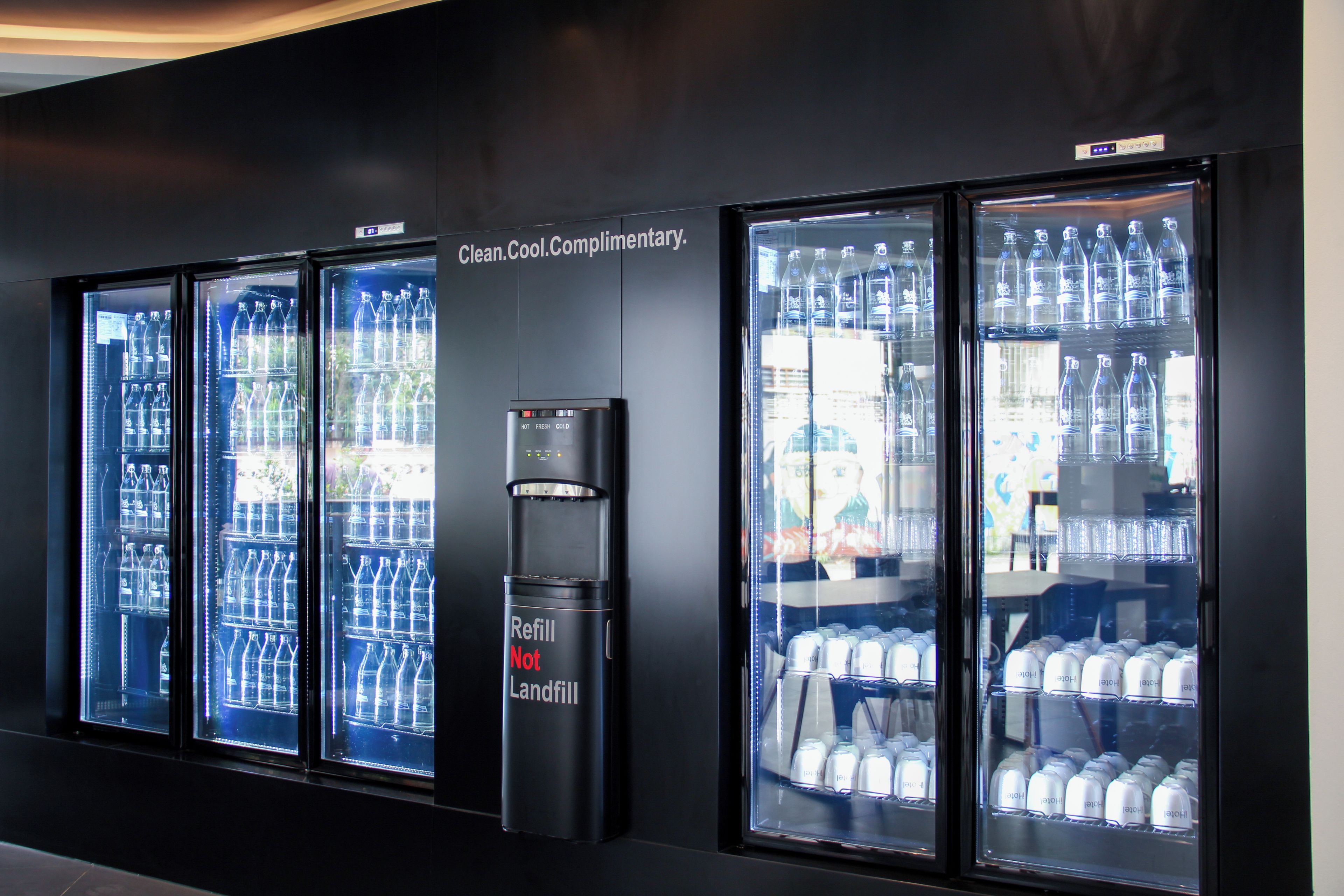 A row of beverage dispensers with a sign above stating 'Clean. Cool. Complimentary.'