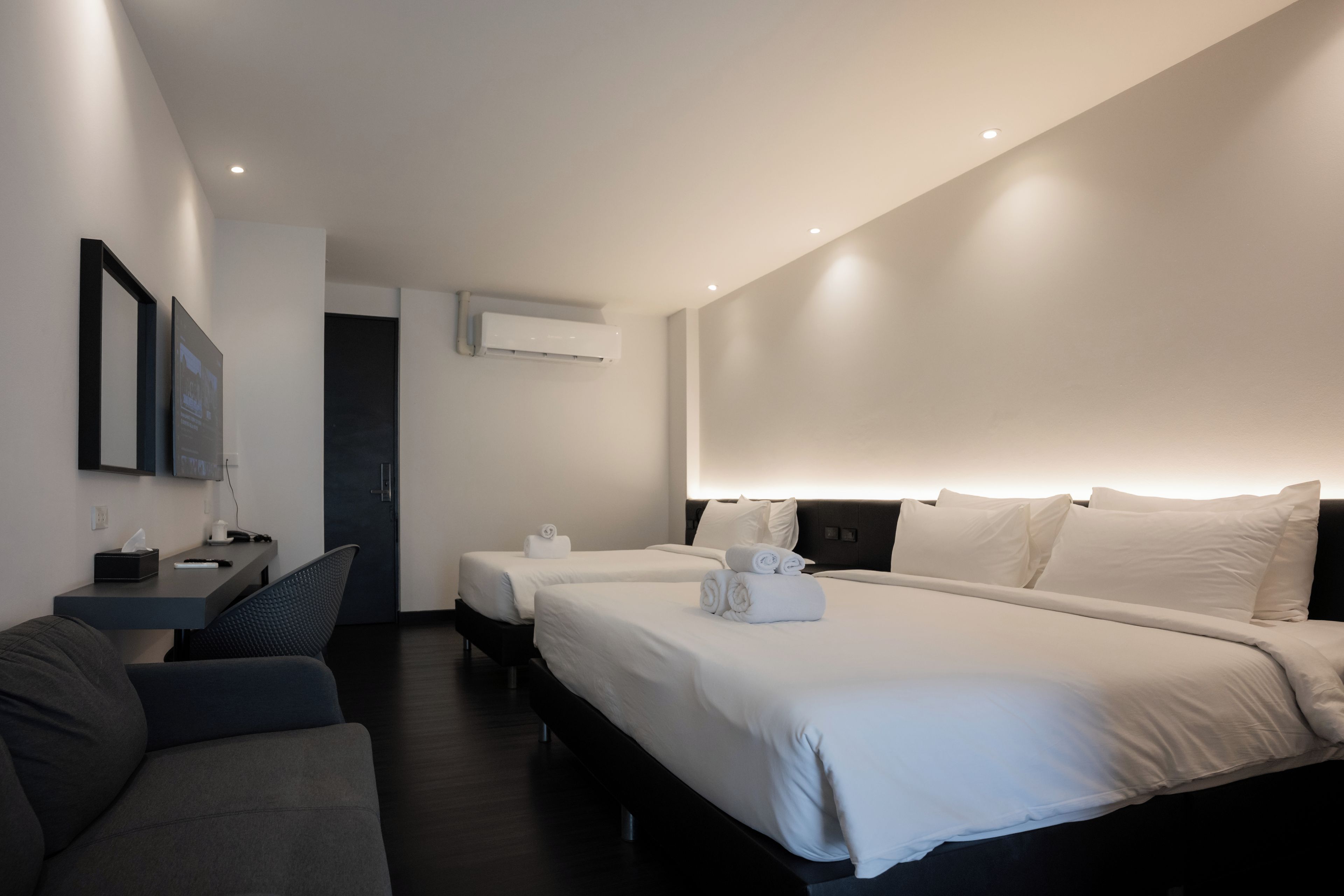 Une chambre d’hôtel moderne équipée de deux lits, d’un bureau et d’un coin salon.
