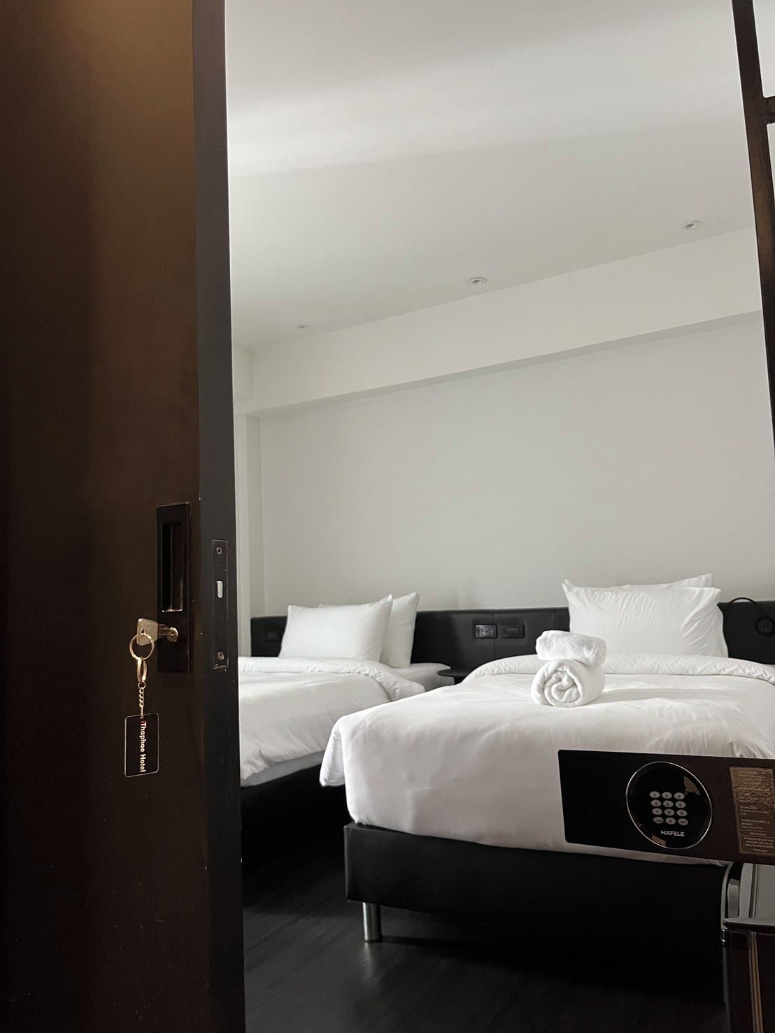 A hotel room with two beds, a control panel, and a keycard holder.