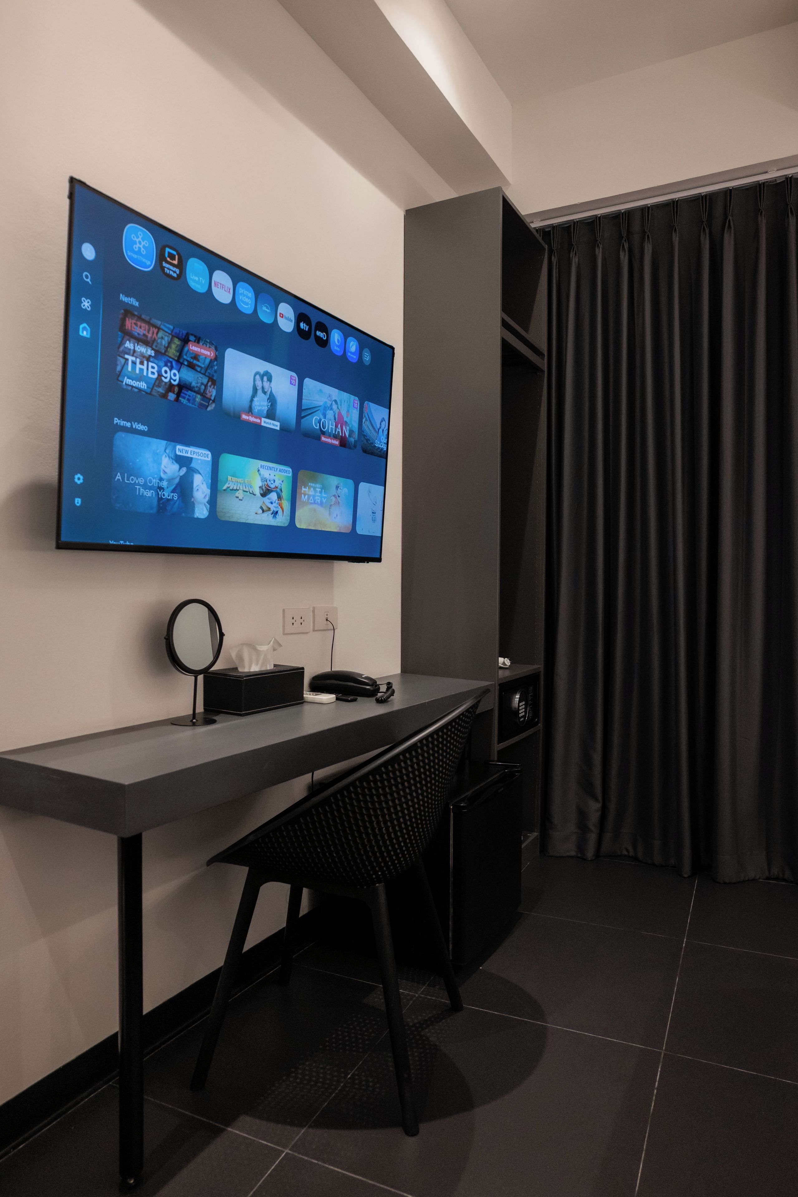 A modern hotel room with a flat-screen TV mounted on the wall displaying various streaming services.