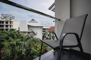 Un balcón con una silla, con vista a una zona residencial con edificios y vegetación.