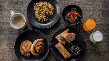 A table with various dishes including fried rice, vegetables, pastries, and a glass of orange juice.