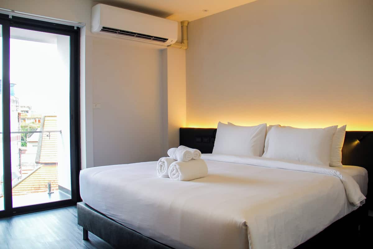 A hotel room with a large bed, a sliding glass door to the outside, and a wall-mounted air conditioner.