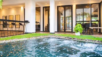 Un área de piscina interior moderna con un jacuzzi, asientos y vistas al exterior.