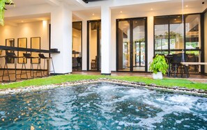 A modern indoor pool area with a hot tub, seating, and a view of the outside. - iThaphae Hotel (Chiang Mai)