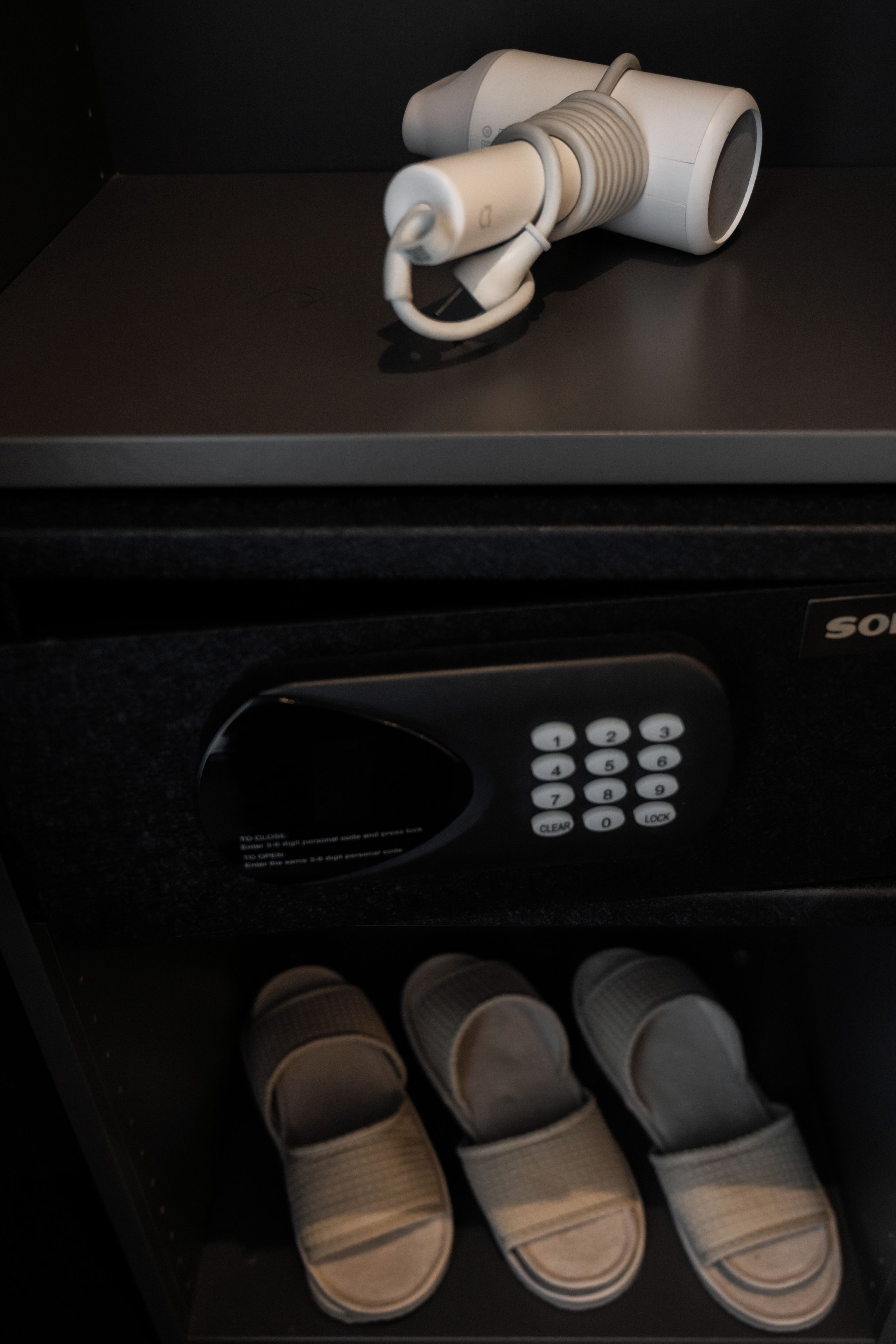 A black suitcase with a remote control and a pair of slippers inside.