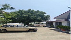 A beige car parked in front of a building with a sloped roof and potted plants. - Hotel Sambodhi (Sanchi)