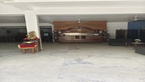 A spacious living room with a large wooden cabinet, a ceiling fan, and a flat-screen TV. - Hotel Sambodhi (Sanchi)