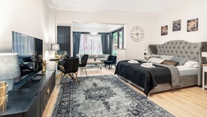 A modern bedroom with a large bed, a desk, and a sofa. - Apartamenty Sun & Snow Granaria (Gdansk)