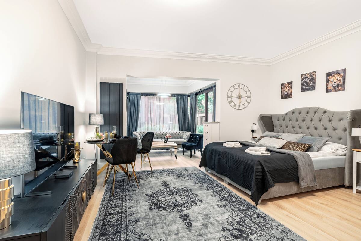 A modern bedroom with a large bed, a desk, and a sofa.