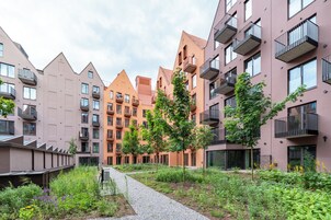 Un moderno complejo de apartamentos con varios edificios, balcones y un jardín con senderos.