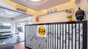 Una reception con il logo 'Itsy Hotels', una statua di Buddha, un orologio e un estintore.