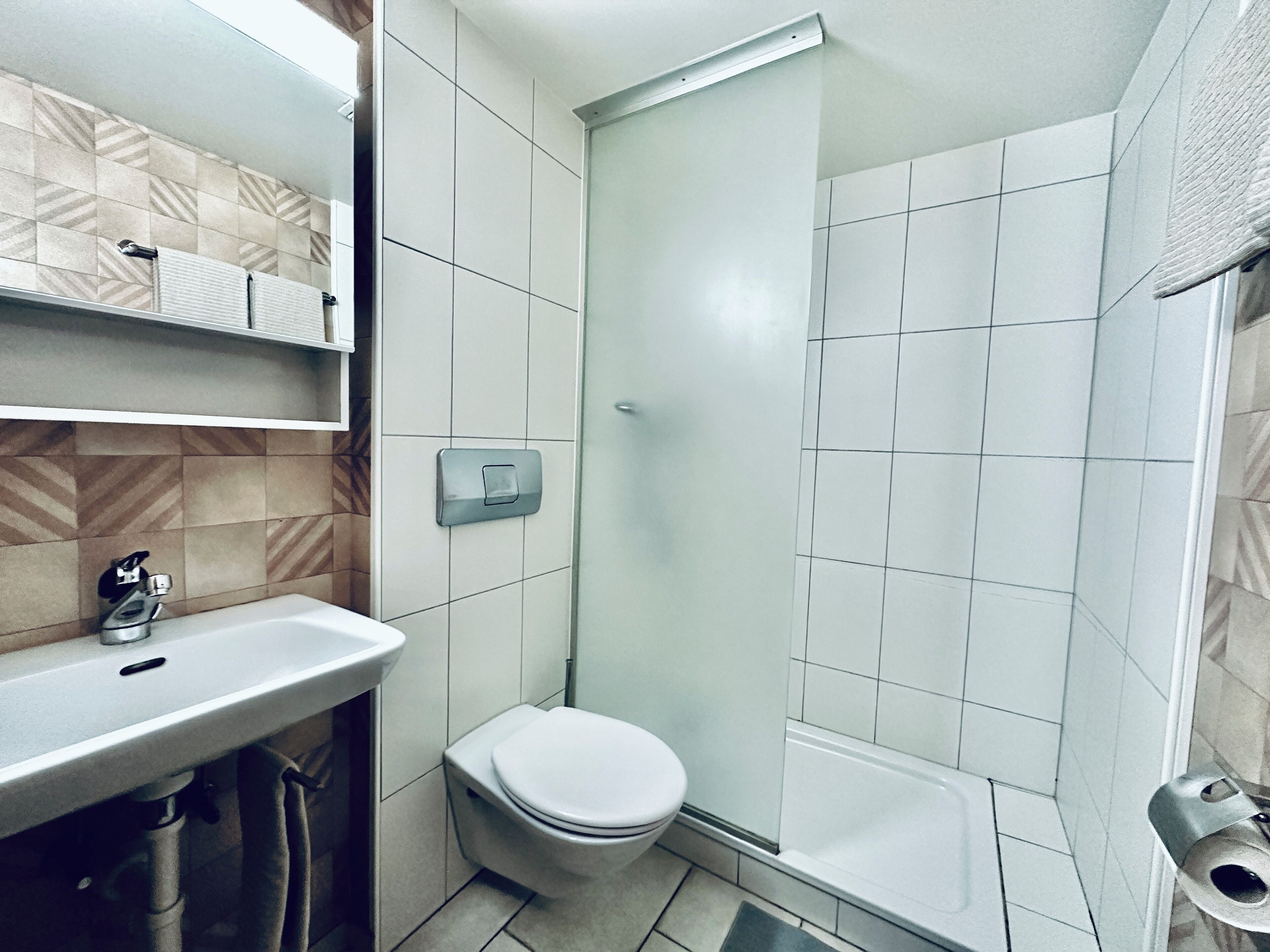 A modern bathroom with a white sink, toilet, and shower.