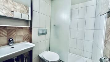 A modern bathroom with a white sink, toilet, and shower.