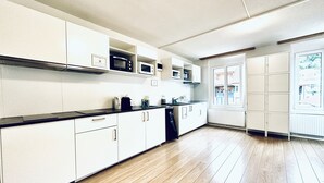 A modern kitchen with white cabinets, a black countertop, and wooden flooring.