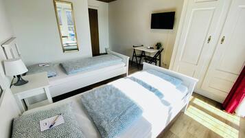 Une chambre avec deux lits, un bureau, une chaise, une télévision et une porte.