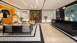 A modern hotel lobby with a reception desk, seating area, and decorative elements. - Fusion Point Hotel (Hue)