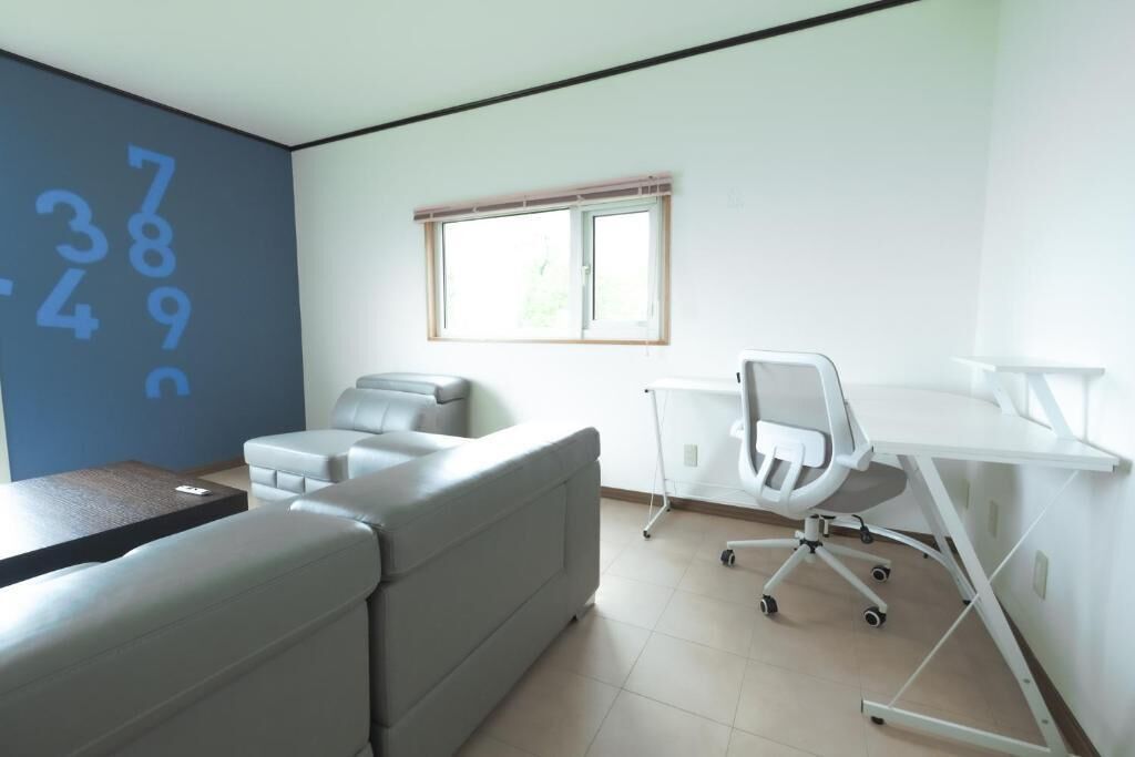 A modern room with a sofa, a desk, and a window with blinds.