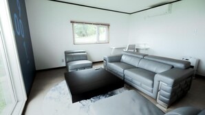 A modern living room with a grey sectional sofa, a small coffee table, and a window with blinds. - Lake Toya and Nakajima (Toyako)