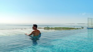 A man in a swimming pool overlooking a beach with a clear view of the ocean and distant land. - h78 Guraidhoo (Guraidhoo)