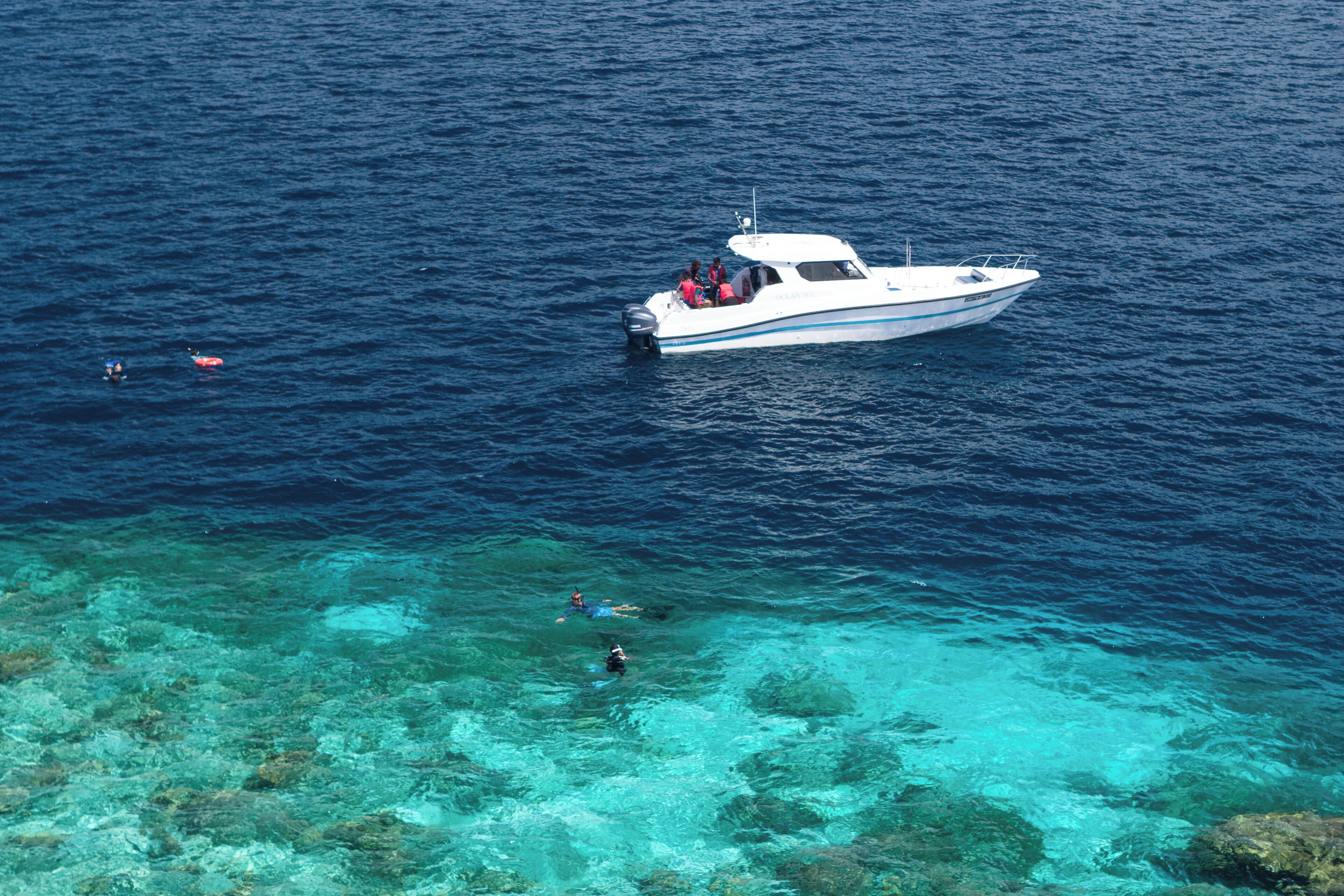 A boat with passengers on a clear blue sea.