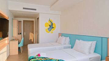 Habitación de hotel con dos camas, un escritorio, una silla y una pared decorada con una obra de arte azul y amarilla.