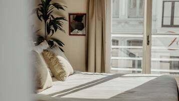Une chambre à coucher avec un lit, une plante en pot et une fenêtre avec des rideaux.