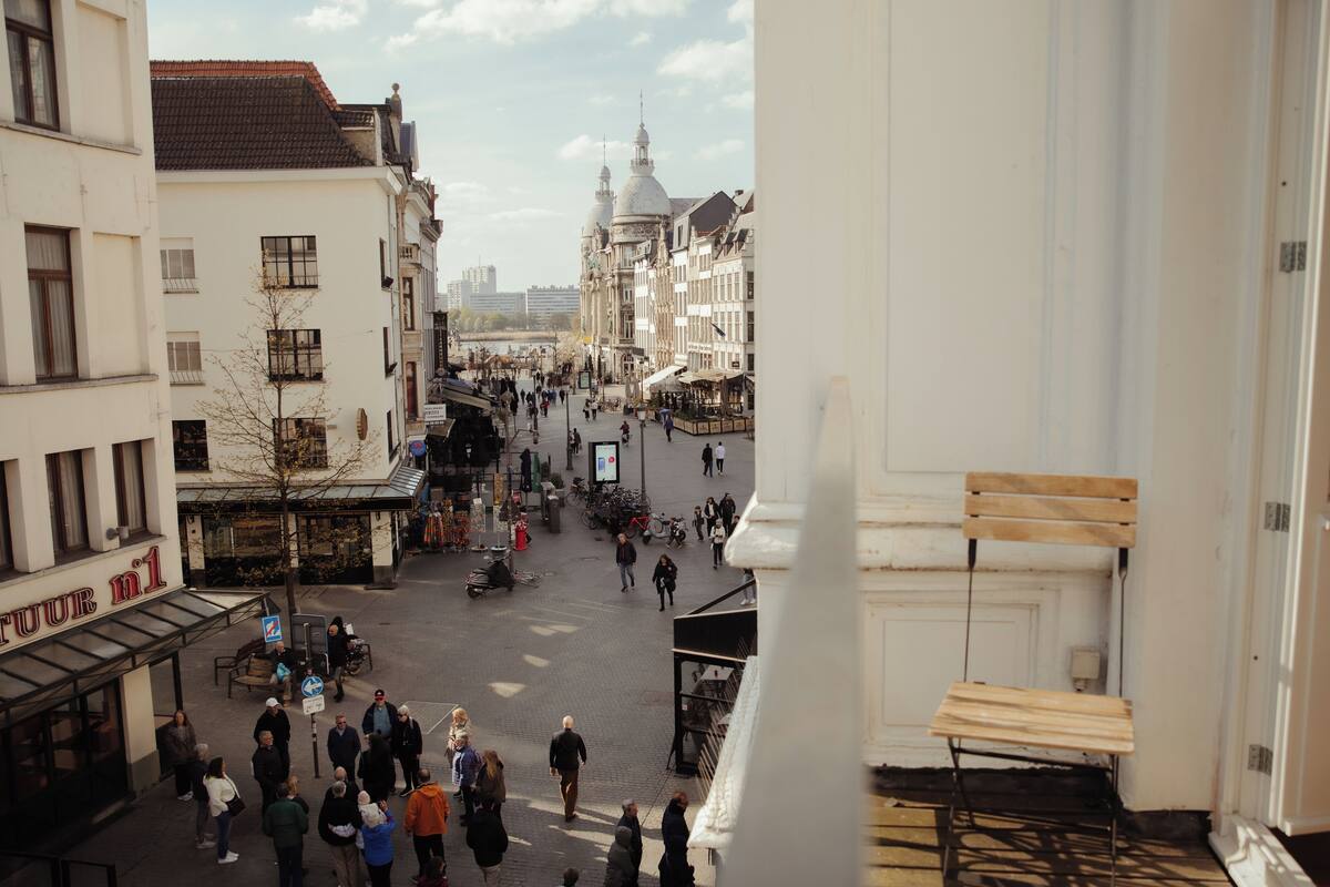 Ein belebter Stadtplatz mit historischen Gebäuden, einem Café und einem sichtbaren Schild mit der Aufschrift 'TOUR n1'.