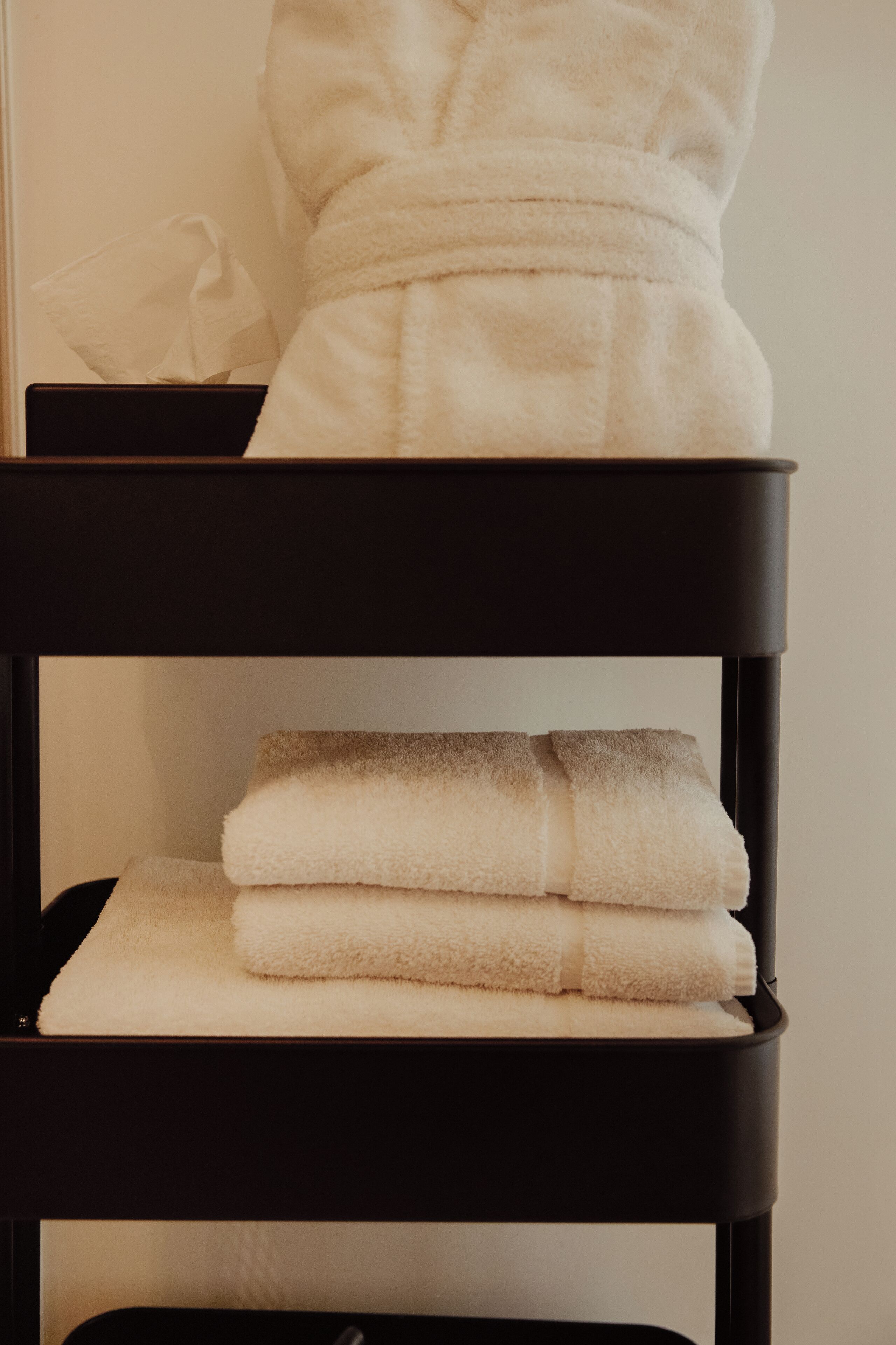 A black shelf with folded towels.