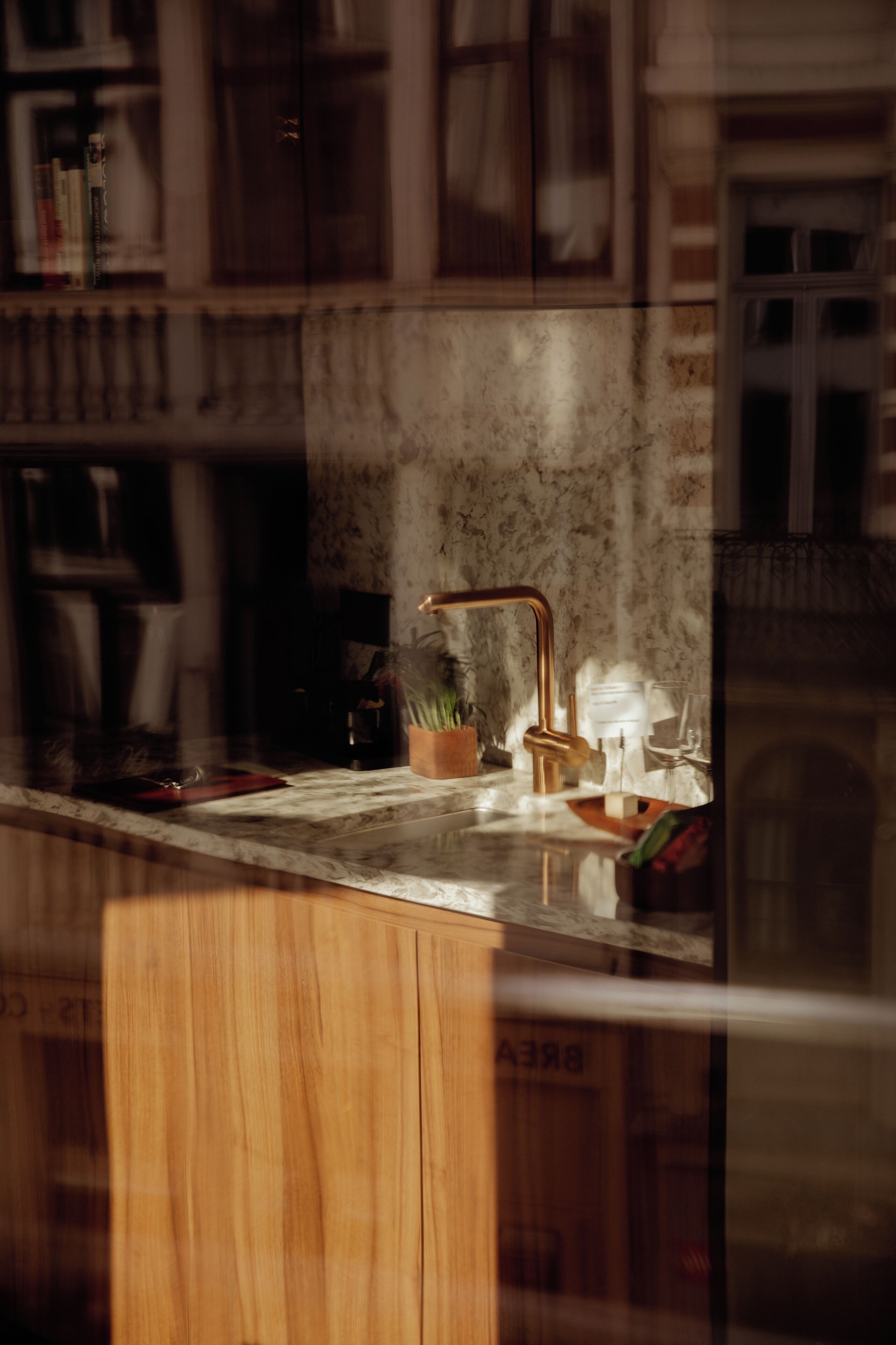 A kitchen with a marble countertop, a copper faucet, and a wooden cabinet.