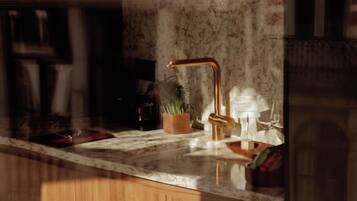 A kitchen with a marble countertop, a copper faucet, and a wooden cabinet.