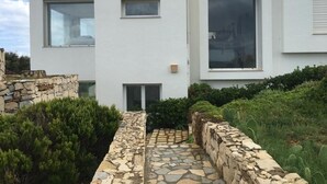 A modern two-story building with large windows, a stone pathway, and surrounding greenery. - Villa with Ocean View in Cap Zebib, Ras Jebel (Ras Jebel)