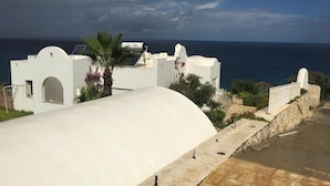 A coastal building with a curved white facade, a palm tree, and a view of the sea. - Villa with Ocean View in Cap Zebib, Ras Jebel (Ras Jebel)