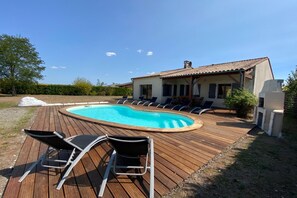 A swimming pool with lounge chairs and a wooden deck. - Charming Apartment in Dordogne Countryside (Chalais)