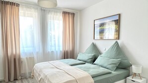 Una camera da letto con un letto, tende, un comodino e una lampada a sospensione.