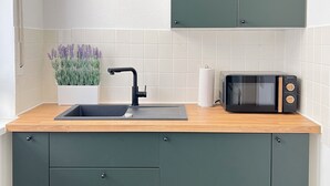 Una cucina con lavello, forno a microonde e pensile.