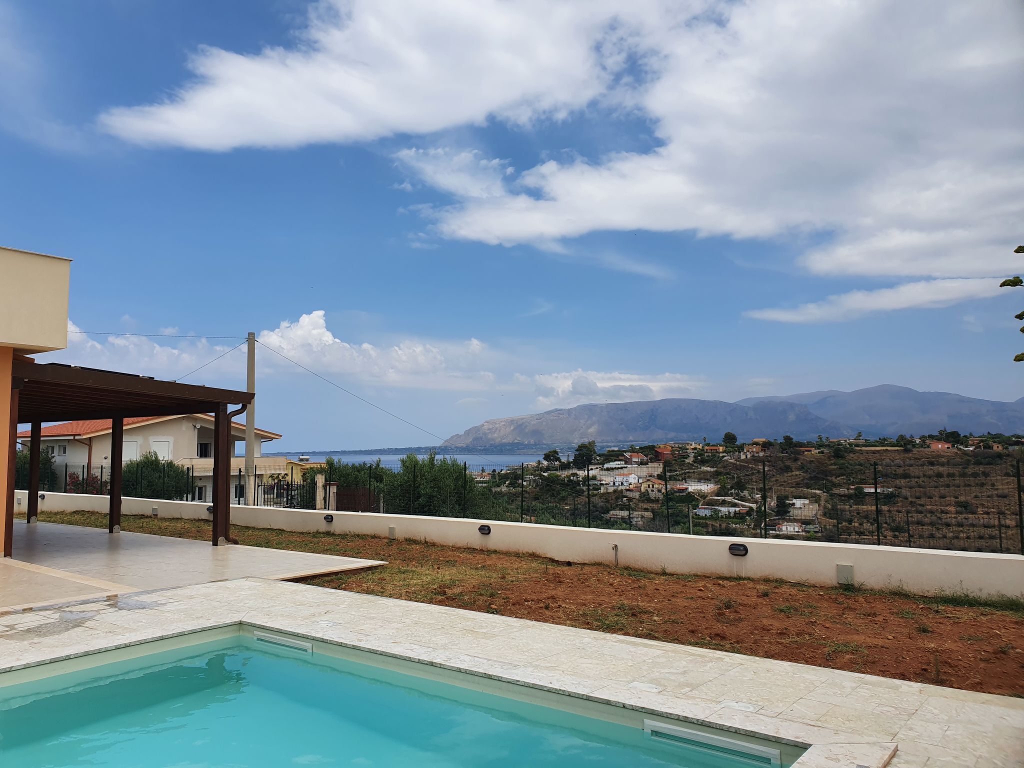 A swimming pool with a view of a coastal town and mountains in the background.