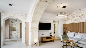 A modern living room with a stone archway, a wooden console table, a sofa, and a TV mounted on the wall.