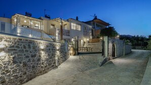A stone-walled building with a gated entrance, a balcony, and a stone pathway leading to the entrance.