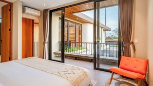 A bedroom with a bed, a chair, a balcony with a view, and a sliding glass door. - The Foglia Canggu (Canggu)