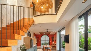 A modern interior with a staircase, a dining area, and a view of a swimming pool. - The Foglia Canggu (Canggu)