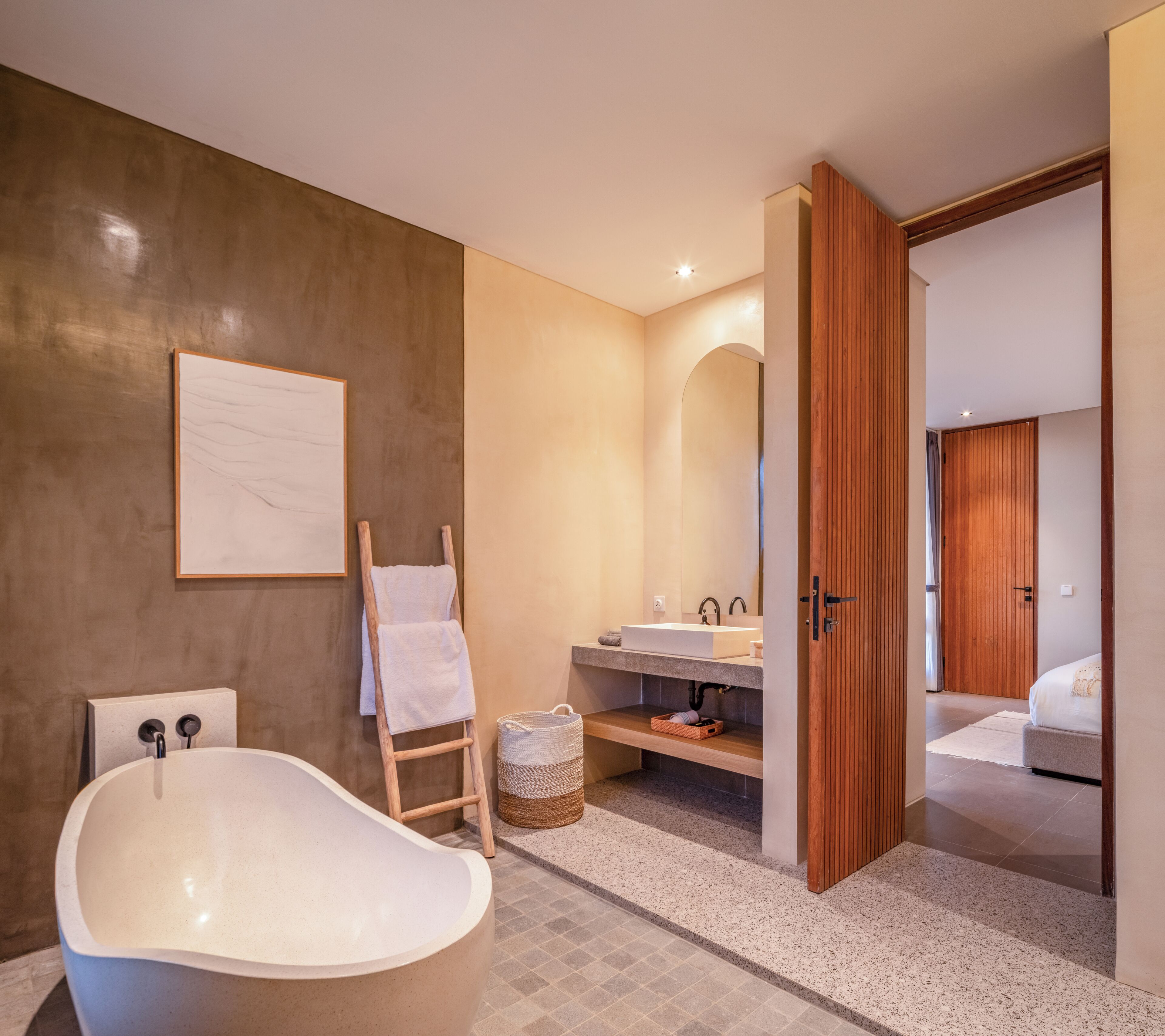 Ein modernes Badezimmer mit einer freistehenden Badewanne, einer Holzleiter, einem großen Spiegel und einem doppelten Waschbecken-Schrank.