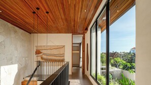A modern interior with a wooden ceiling, a staircase, and large windows overlooking greenery. - The Foglia Canggu (Canggu)