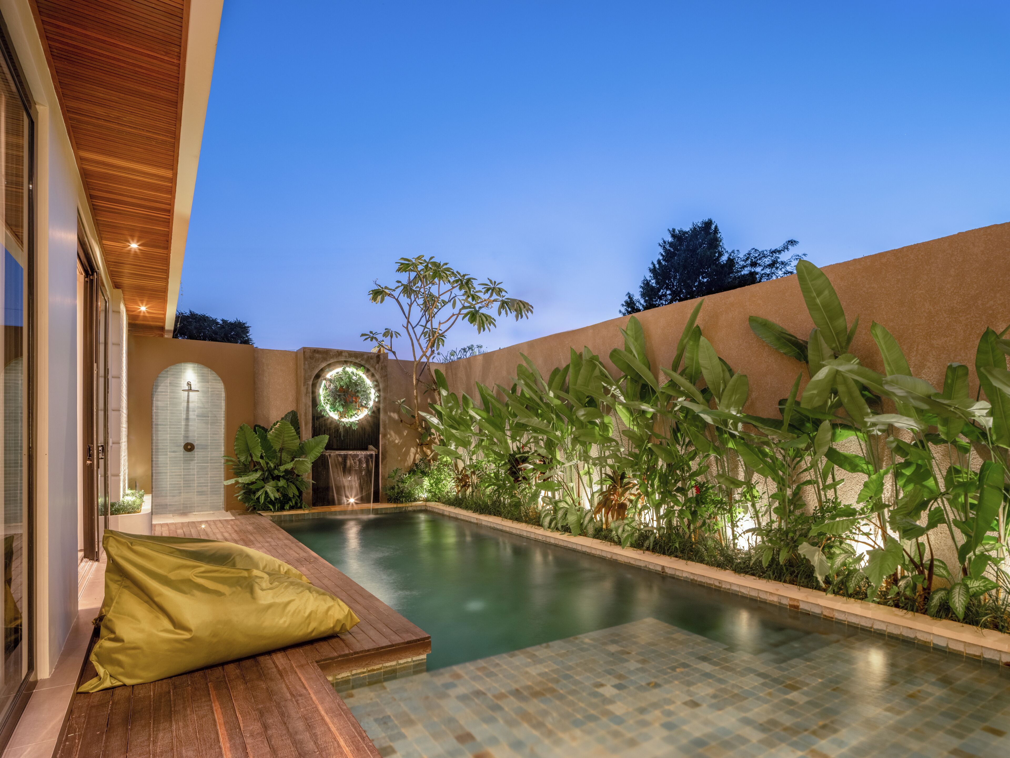 Una piscina con un solarium in legno e una zona relax coperta.
