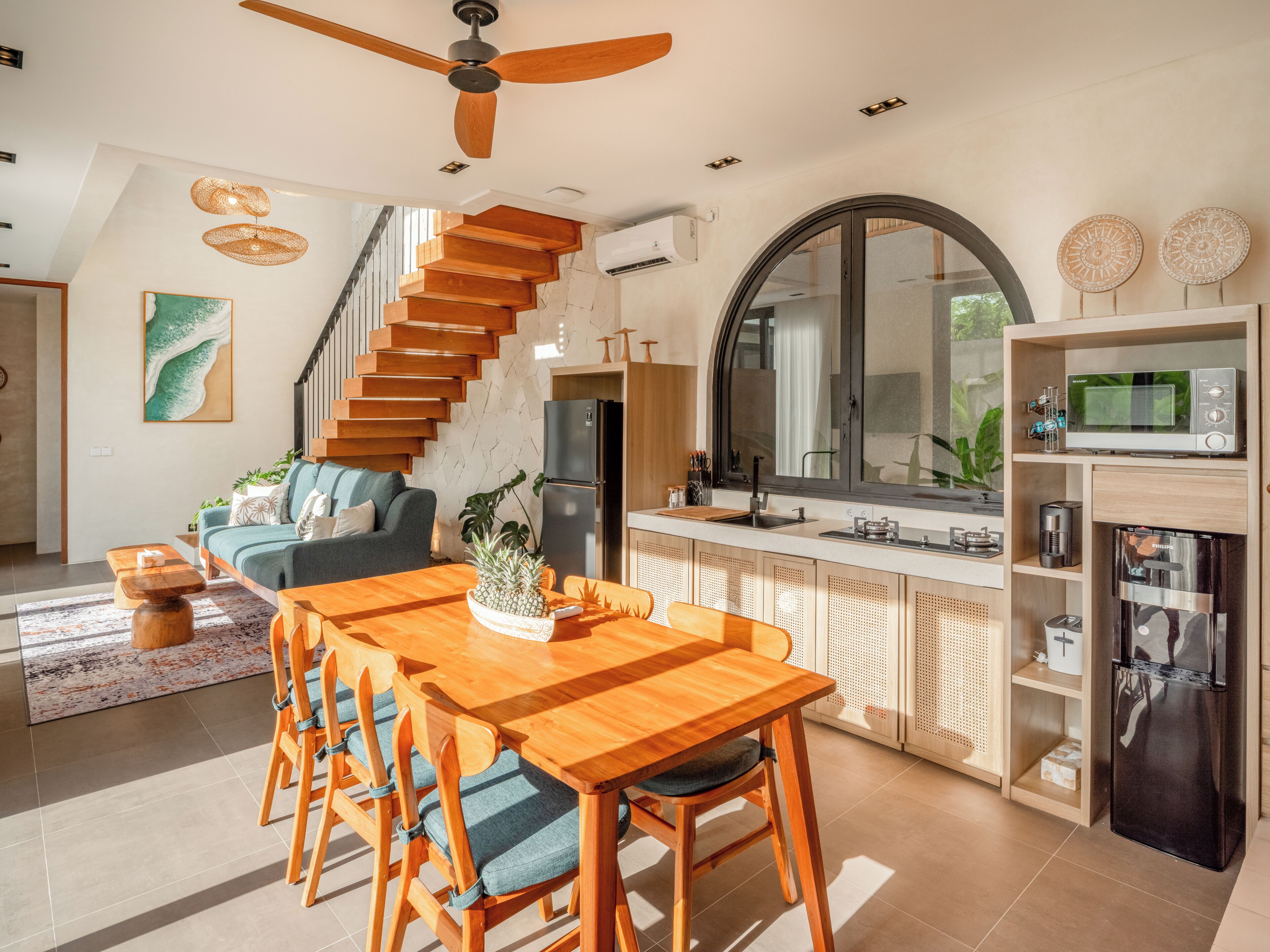 A modern kitchen with a wooden dining table, chairs, a built-in oven, and a large window.