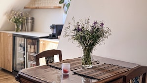 A dining table with a vase of flowers, a glass of drink, and a woven placemat.